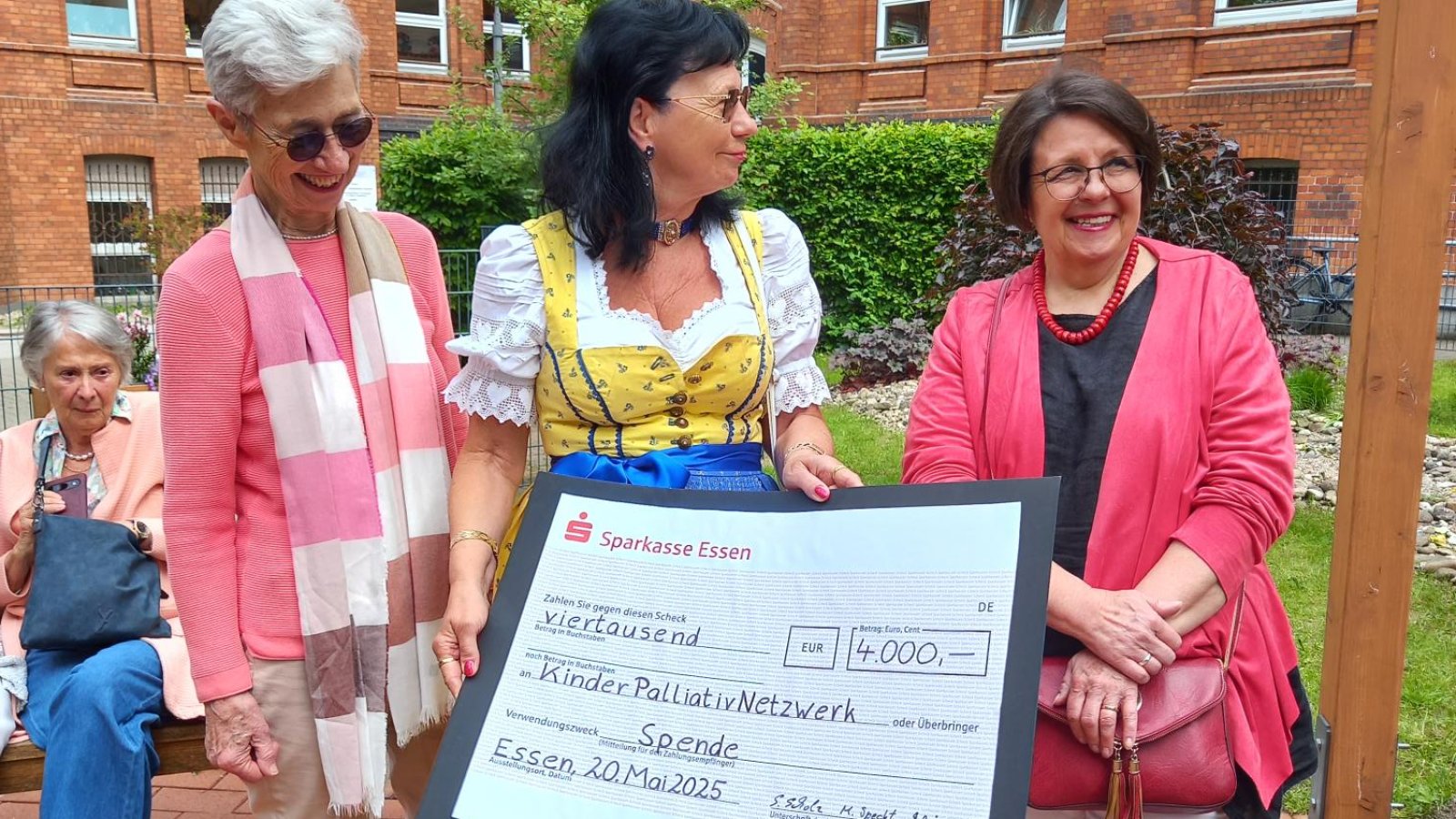 Drei Frauen übergeben einen symbolischen Scheck mit einer Geldsumme von 4.000 Euro