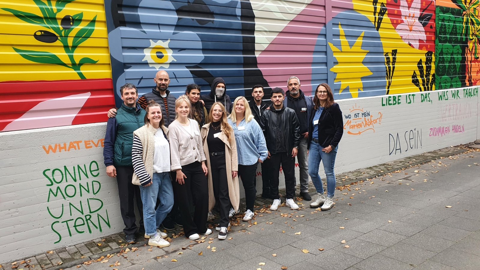 Eine Gruppe von Menschen vor einer Lärmschutzwand