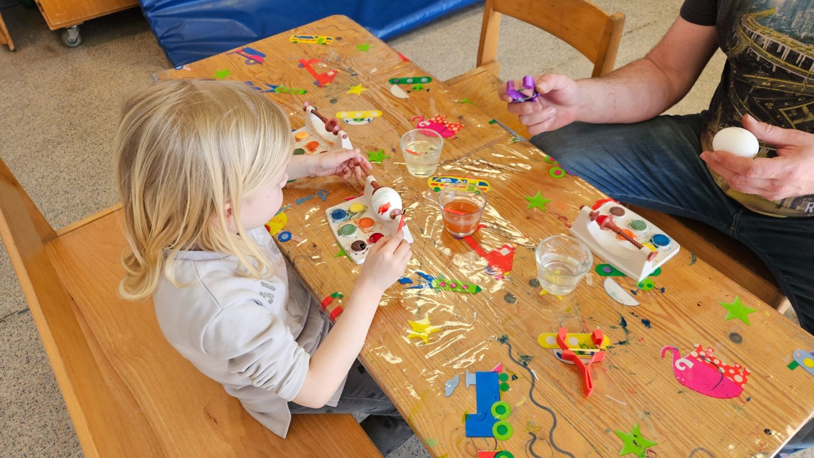 Kind sitzt mit Vater beim Malen und Basteln am Tisch