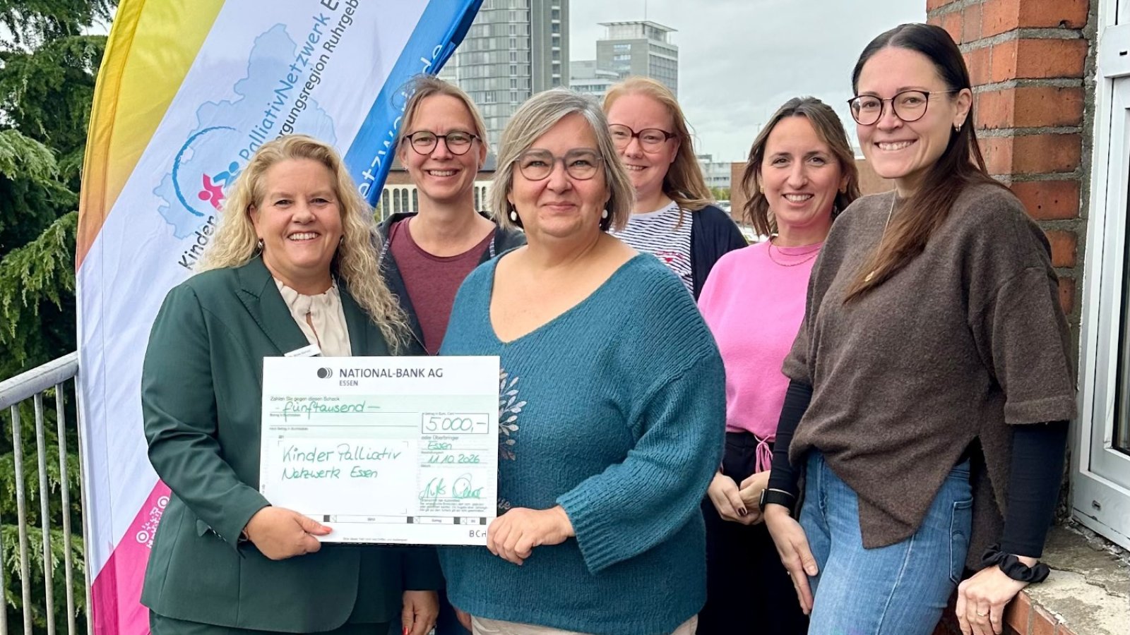 Eine Gruppe von Menschen mit einem symbolischen Scheck zur Spendenübergabe an das KinderPalliativNetzwerk