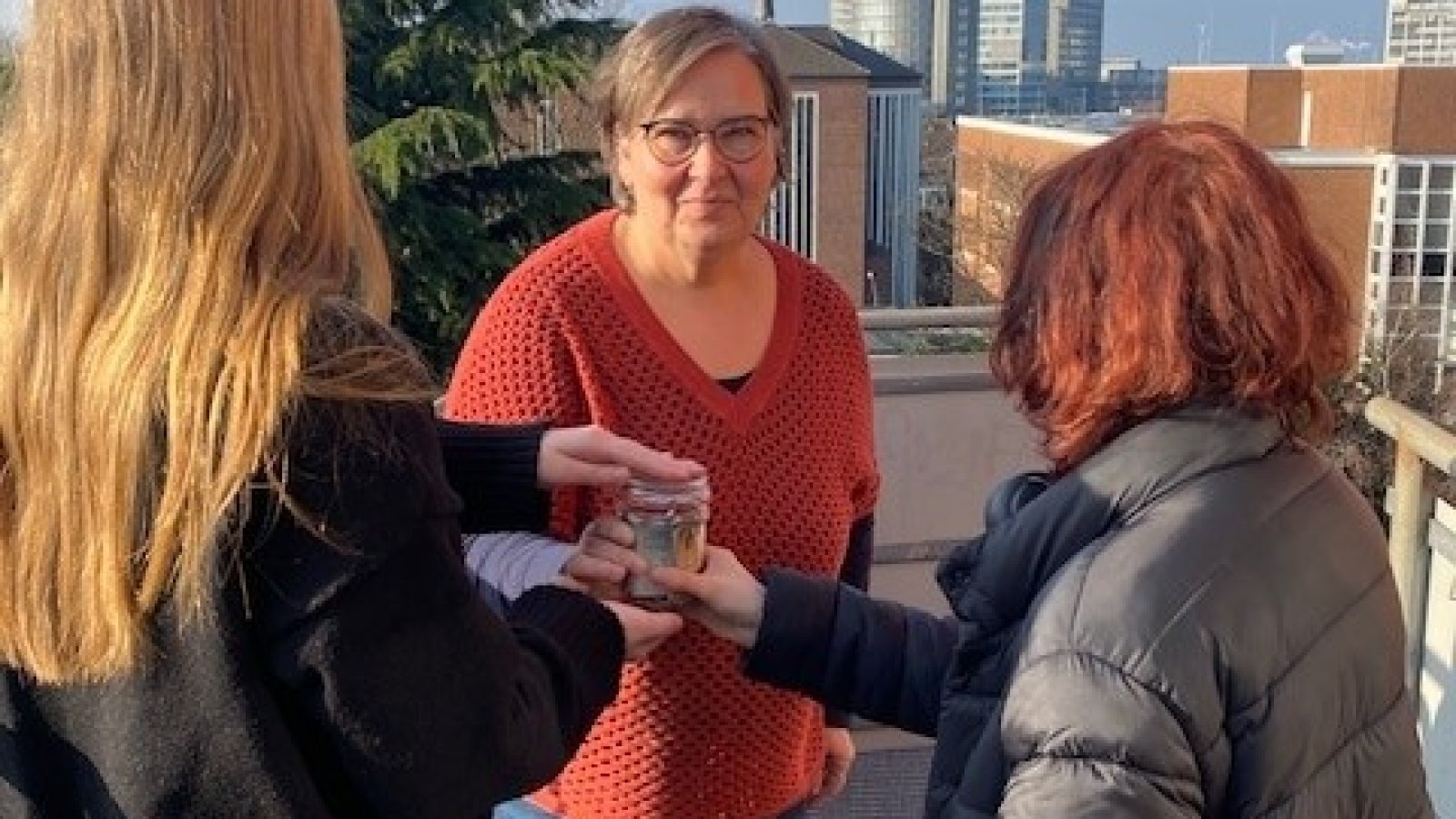 zwei Mädchen übergeben Glas mit Geld