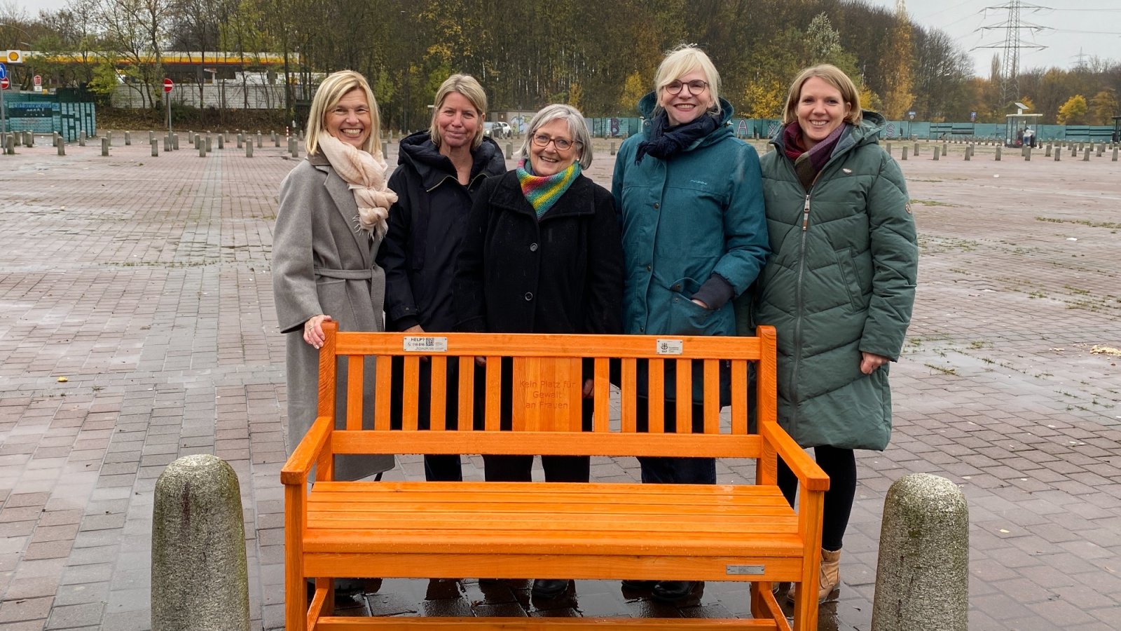 Orangefarbene Bank, dahinter Gruppe Frauen