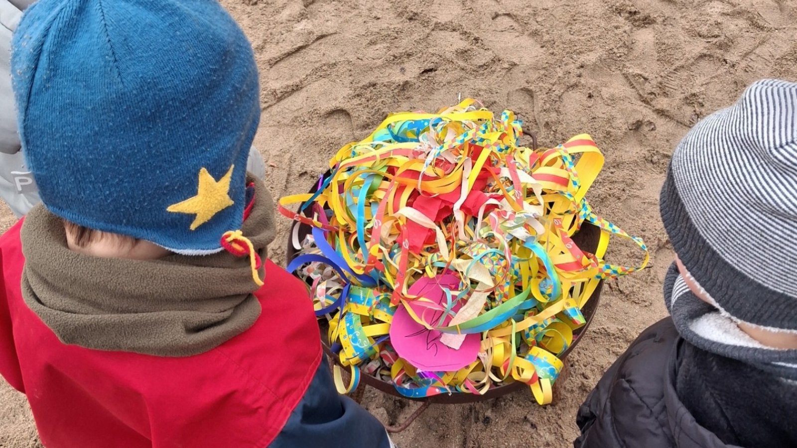 Kinder an Feuerschale voller Konfetti und Luftschlangen