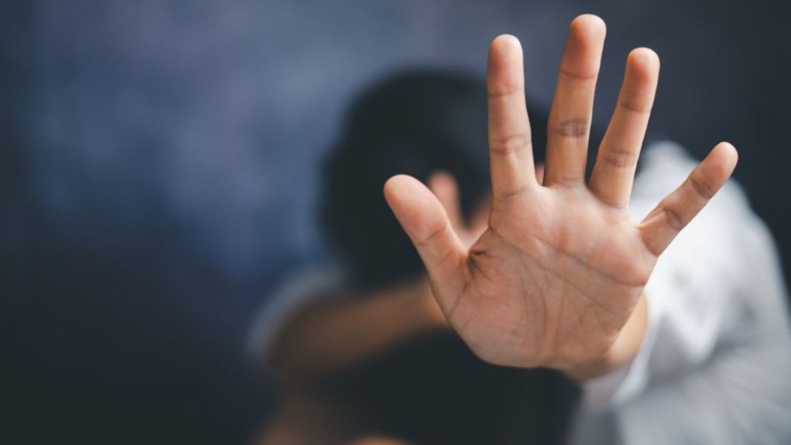 Sitzende Frau hält abwehrend Hand hoch