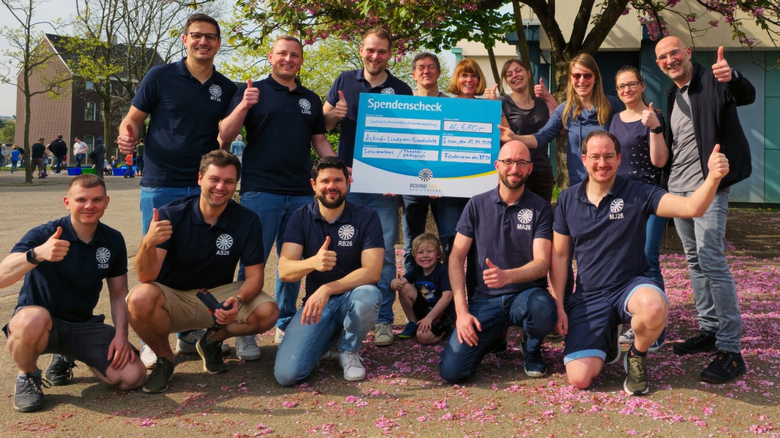 Eine Gruppe von Menschen in blauen T-Shirts hält einen großen Scheck.