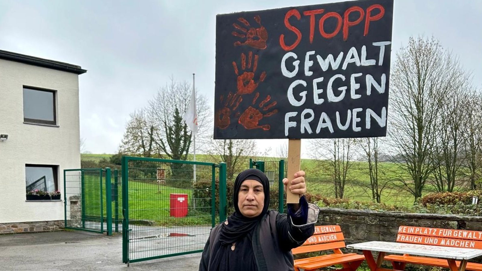 Frau mit Kopftuch und Schild auf dem Steht