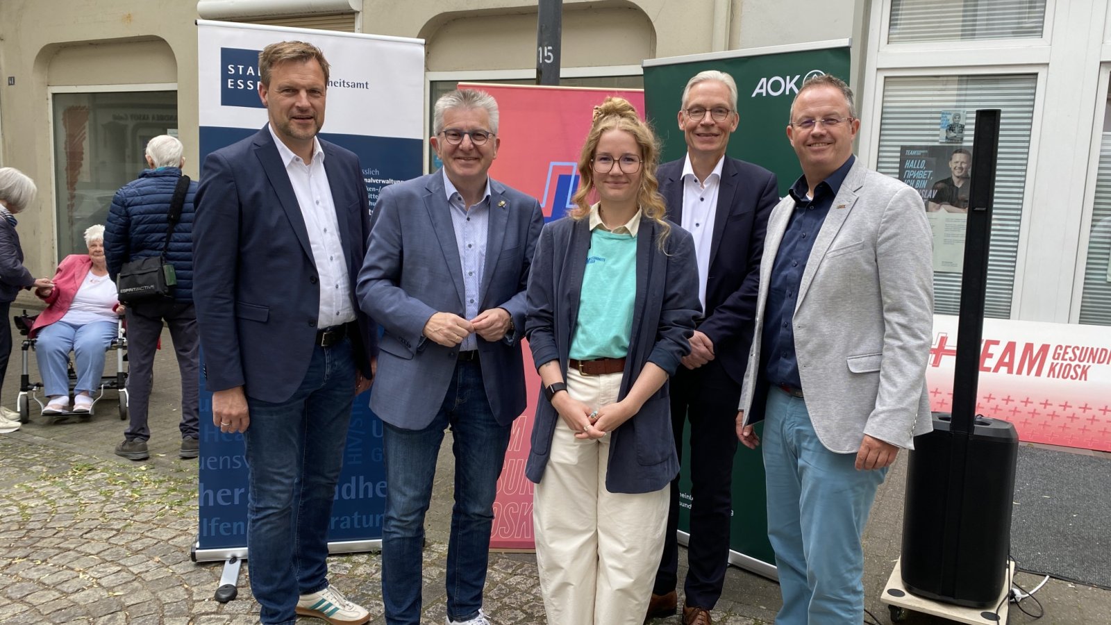 Eine Gruppe von fünf Personen steht vor dem Gebäude.  