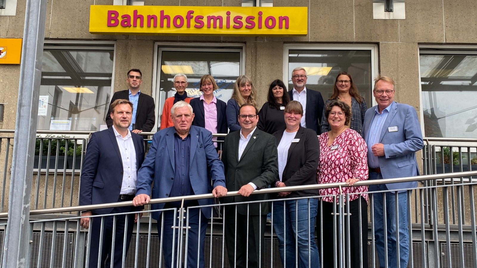 Menschengruppe steht vor Schild der Bahnhofsmssion