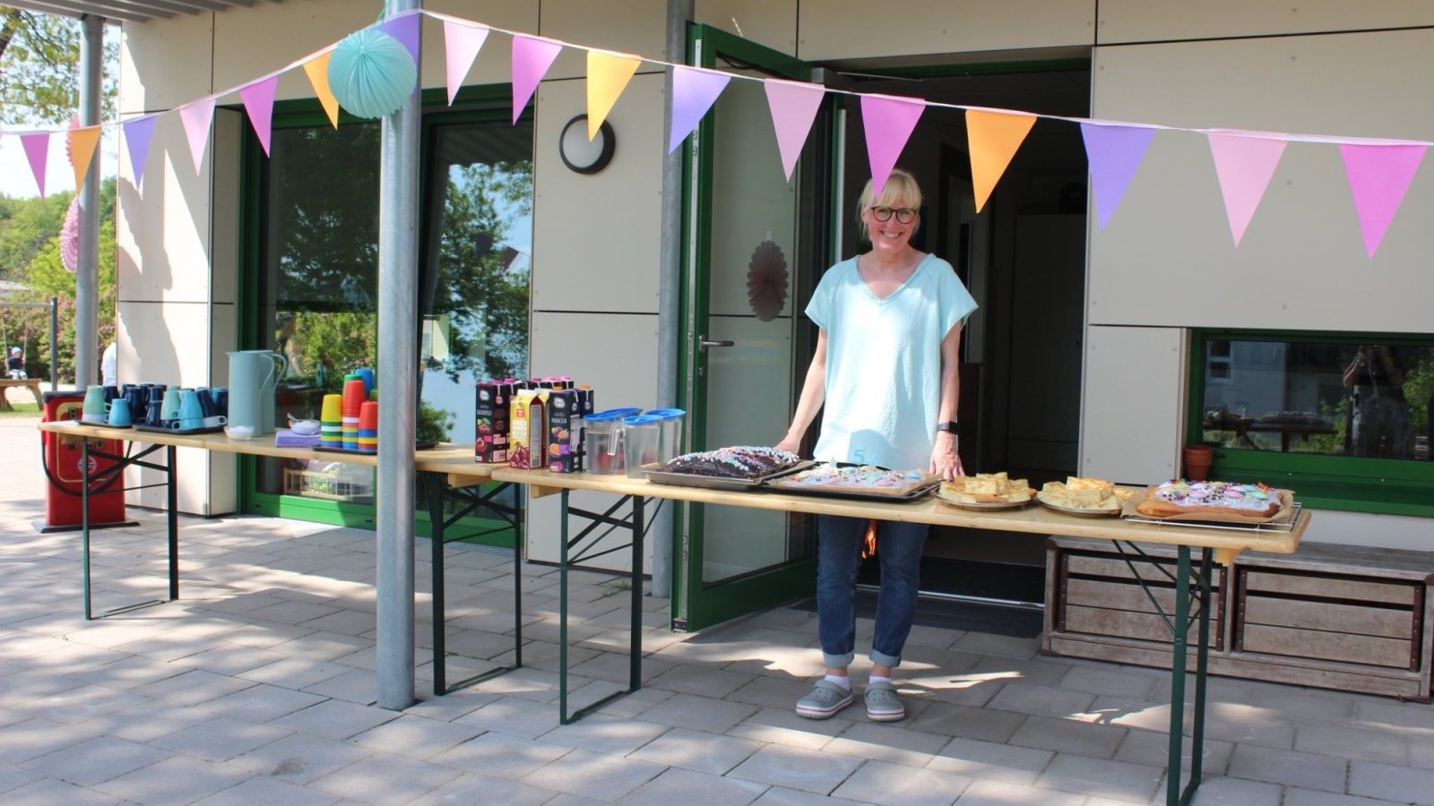 Frau steht hinter Biertisch mit Kuchen