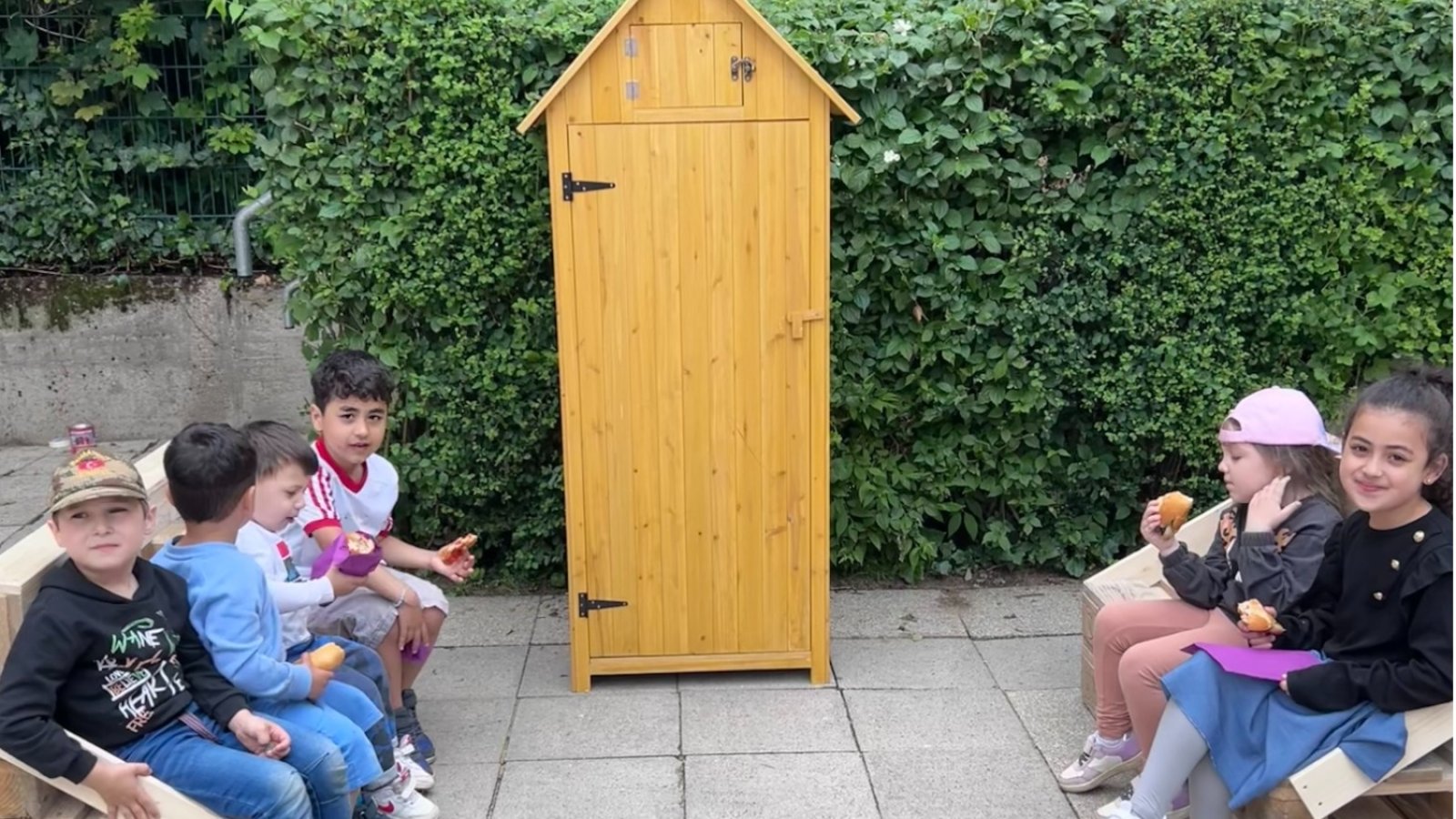 Links und rechts Kinder, in der Mitte ein Bücherschrank