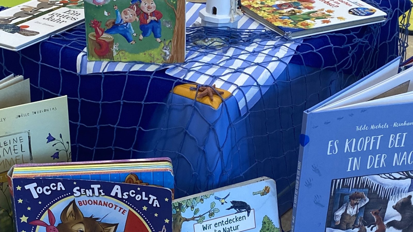 Ausgestellte Bücher rund um einen kleinen Miniaturleuchtturm