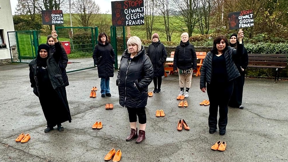 Frauen stehend im Kreis zwischen orangenen Schuhen