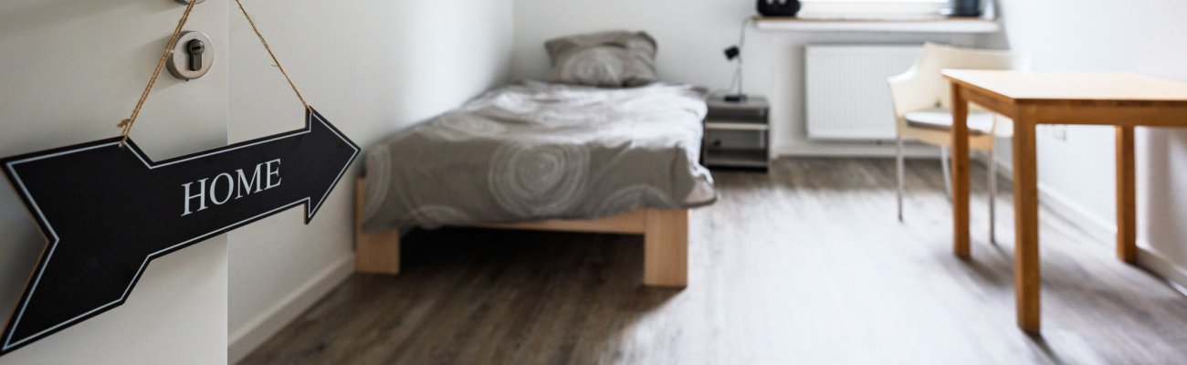 Blick in ein Zimmer mit Bett, Tisch und Stuhl
