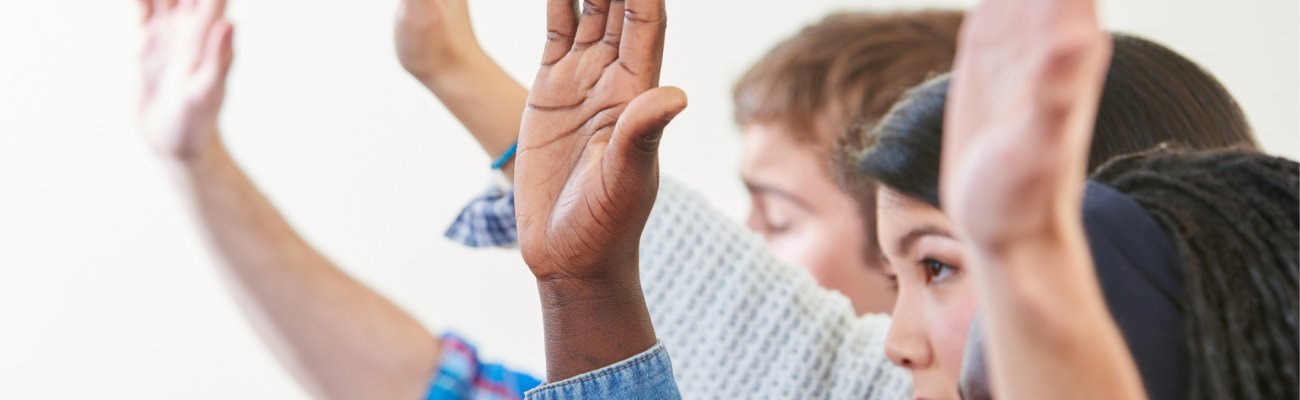 Mehre Personen heben Hände zum Abstimmen