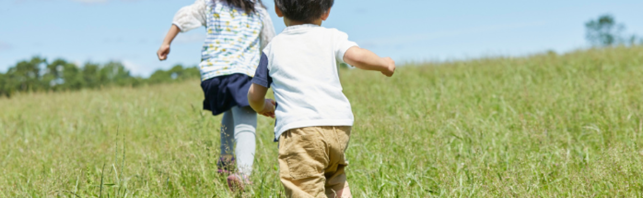 zwei Kinder laufen über Wiese